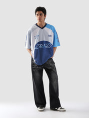 Full body view of man wearing oversized blue and white racing jersey with black baggy jeans and sneakers – Groovy Culture streetwear look Pakistan
