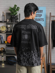 Back view of male model wearing “Groovy Effect” t-shirt in black, with bold screenprinted quote and “Love Over Fear” graphic in grey tones.