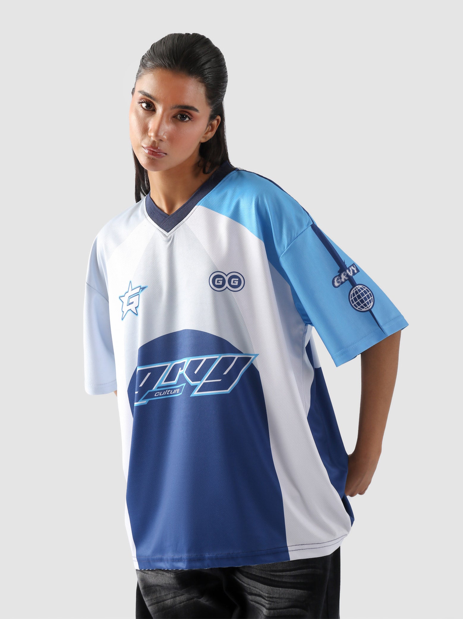 Woman wearing oversized blue and white racing jersey with bold graphics – Groovy Culture unisex streetwear shot in lifestyle indoor setup Pakistan
