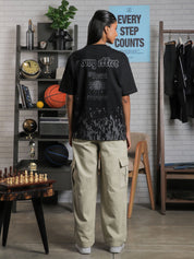 Back view of female model wearing oversized “Groovy Effect” t-shirt with screenprinted motivational text and washed pattern near hem.