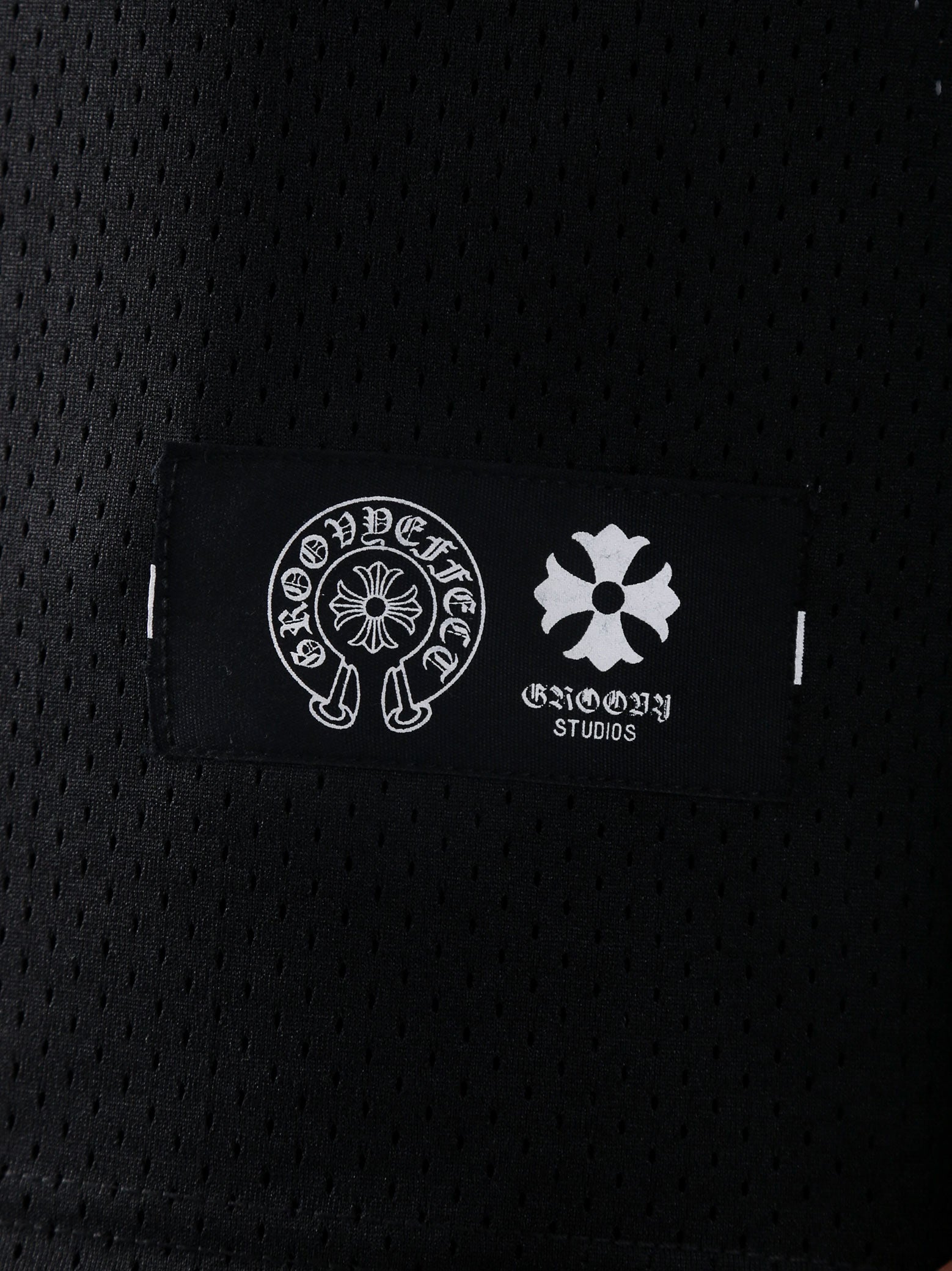 Detailed view of GROOVY's Chrome Hearts-inspired logo label on the black mesh fabric.