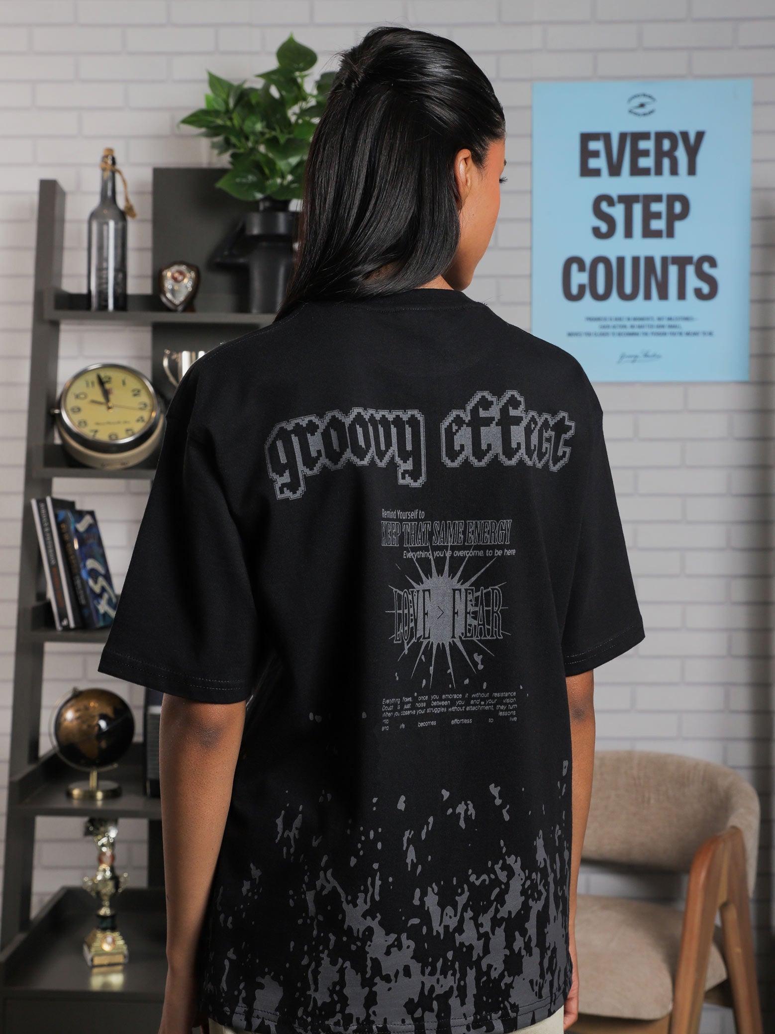 Close-up of back graphic on black oversized t-shirt featuring “Groovy Effect” and “Love Over Fear” typography, screenprinted in grey ink.