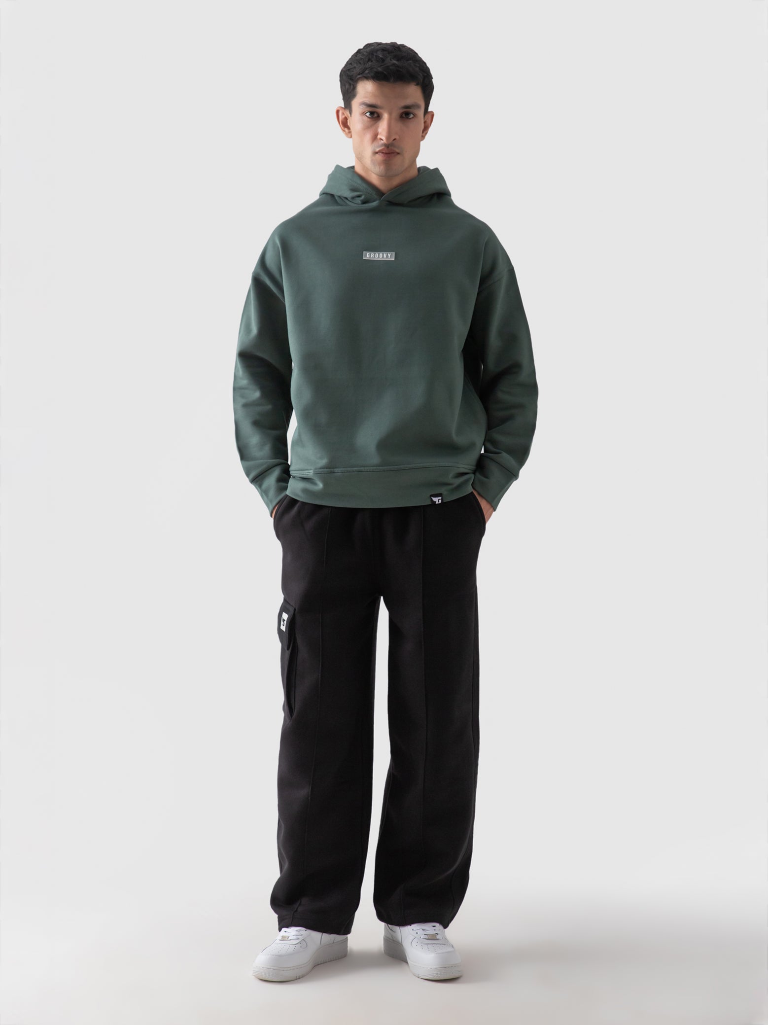 Hunter green oversized hoodie male model seated lifestyle Pakistan – GROOVY