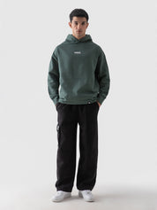 Hunter green oversized hoodie male model seated lifestyle Pakistan – GROOVY