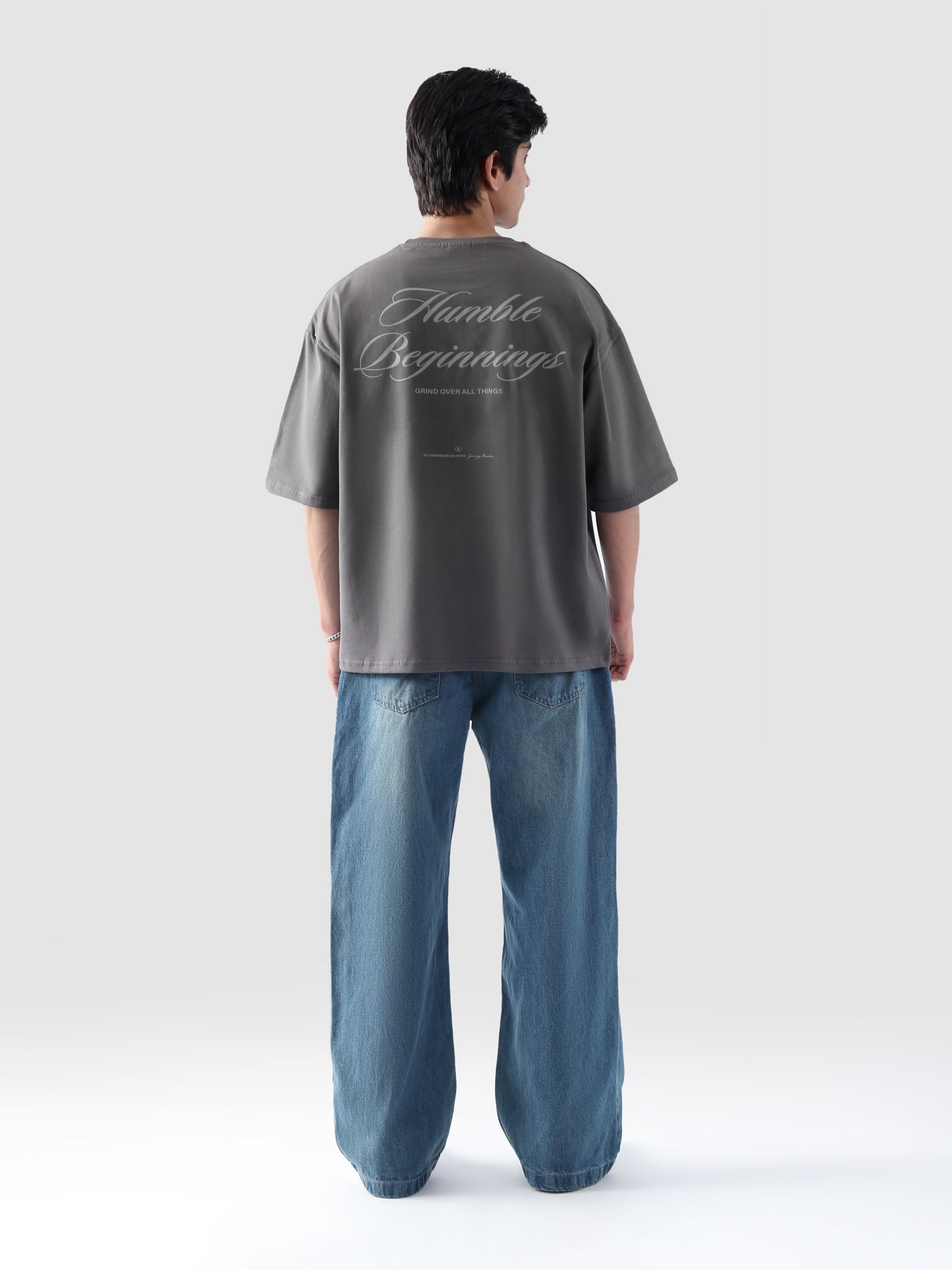 Back view of man wearing grey oversized t-shirt with 'Humble Beginnings' text – baggy streetwear tee by Groovy Pakistan
