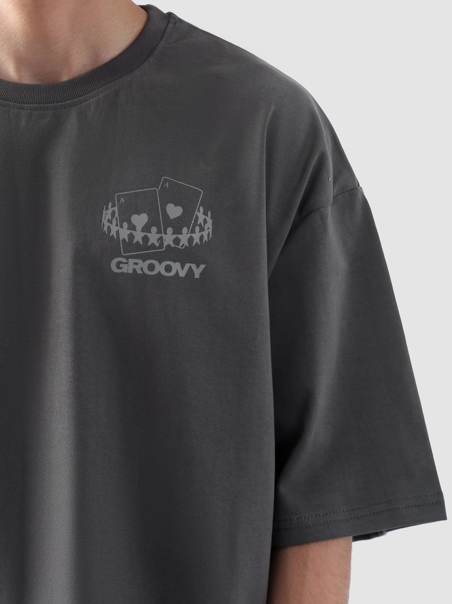 Male model wearing stone grey oversized t-shirt in Pakistan by Groovy – drop shoulder, baggy fit graphic tee styled with loose denim jeans